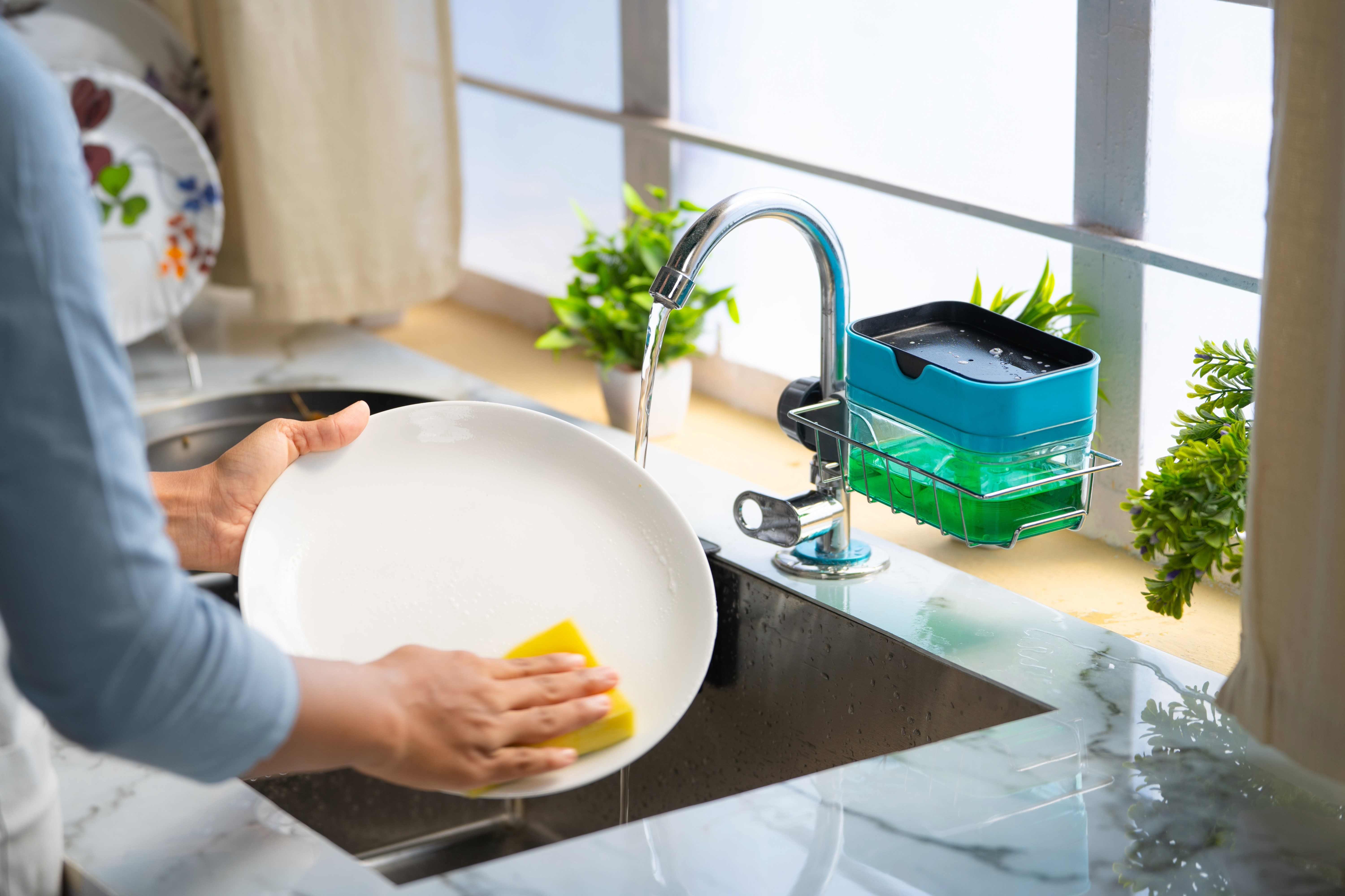 A person washing dishes in the kitchen sink.