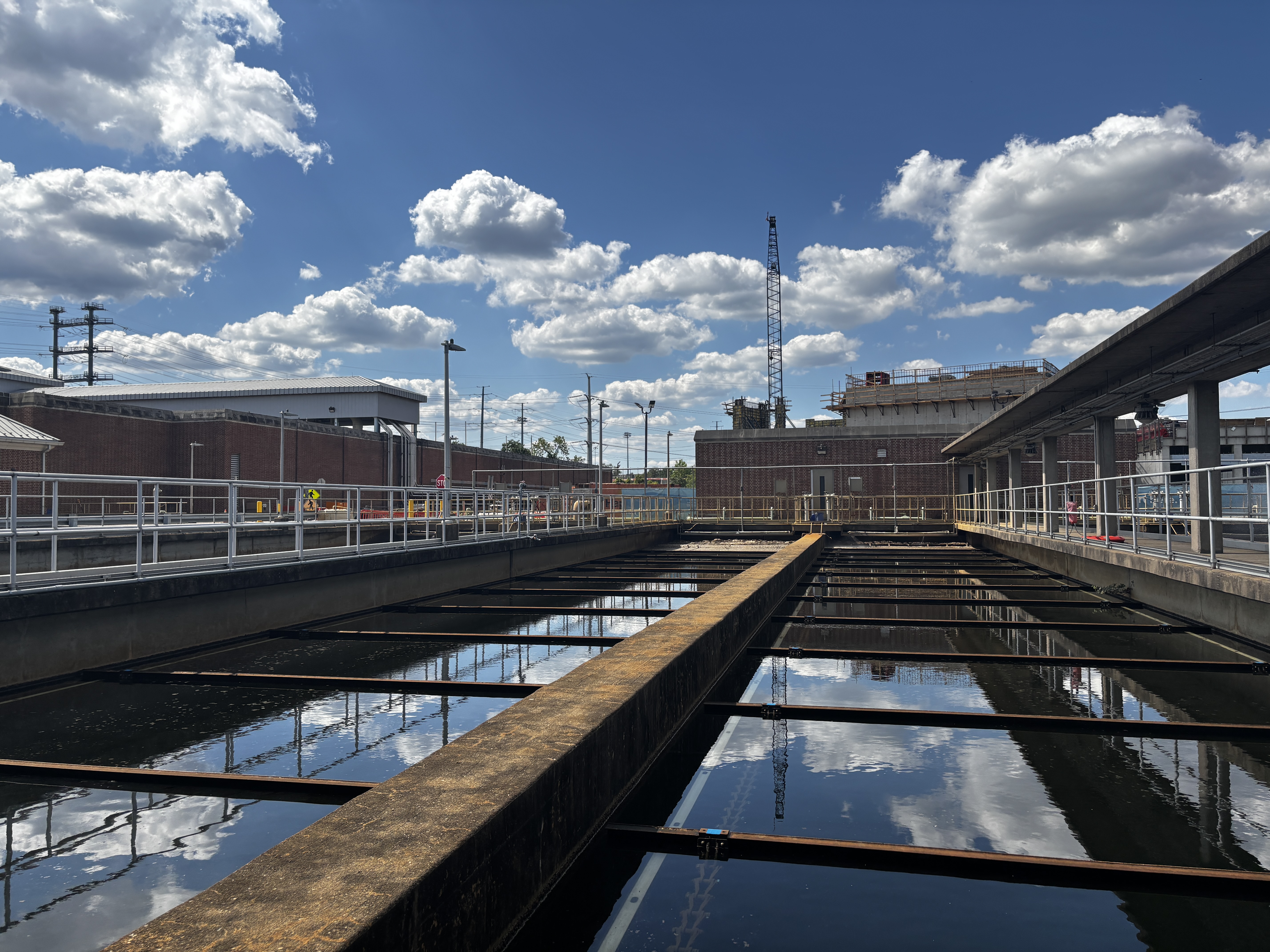 A view of treatment tanks reflecting a blue sky with clouds