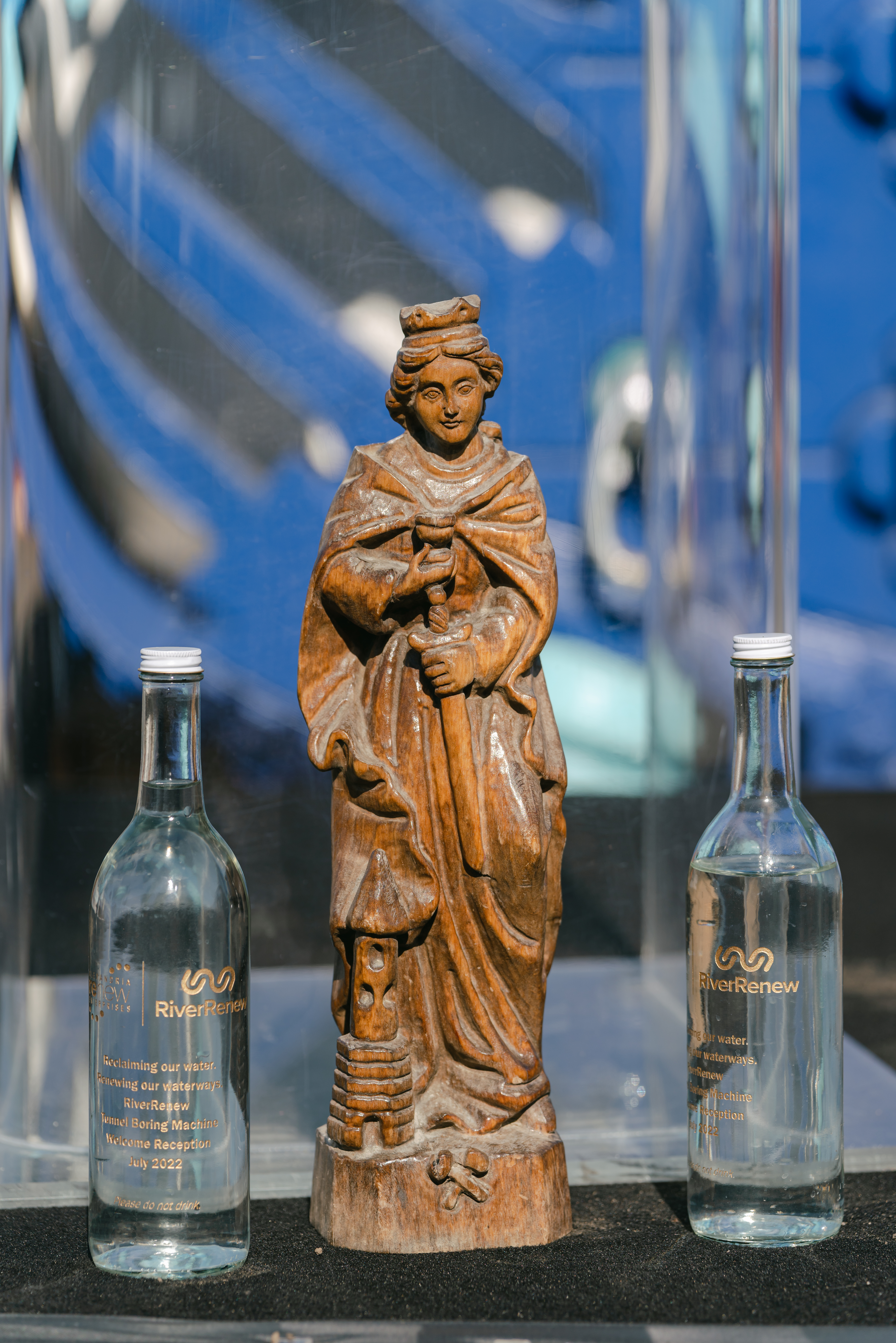 Image of a small statue of a woman, with two glass bottles of water on either side