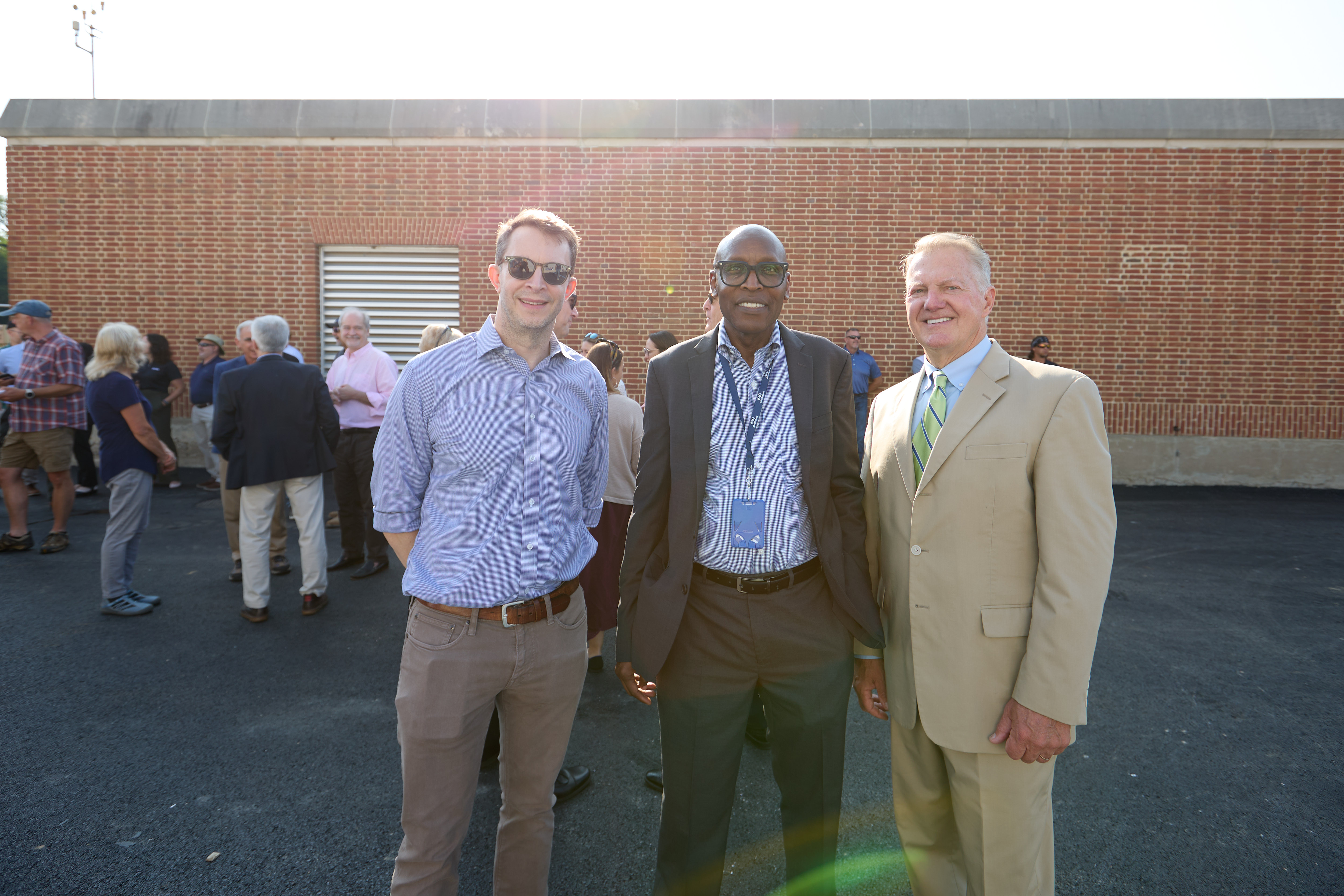 three men in suits smile at the camera.