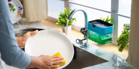 A person washing dishes in the kitchen sink.